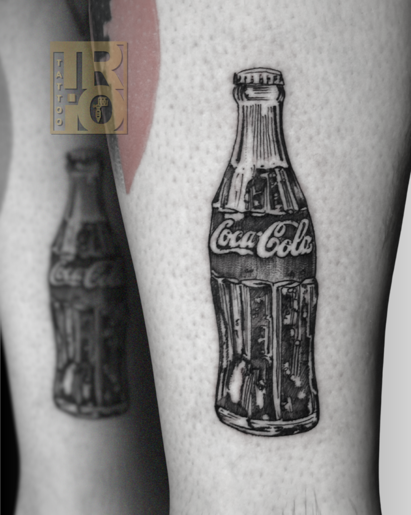tatuaggio Coca Cola black and grey sulla gamba con bottiglietta iconica in stile illustrativo e dettagli vintage